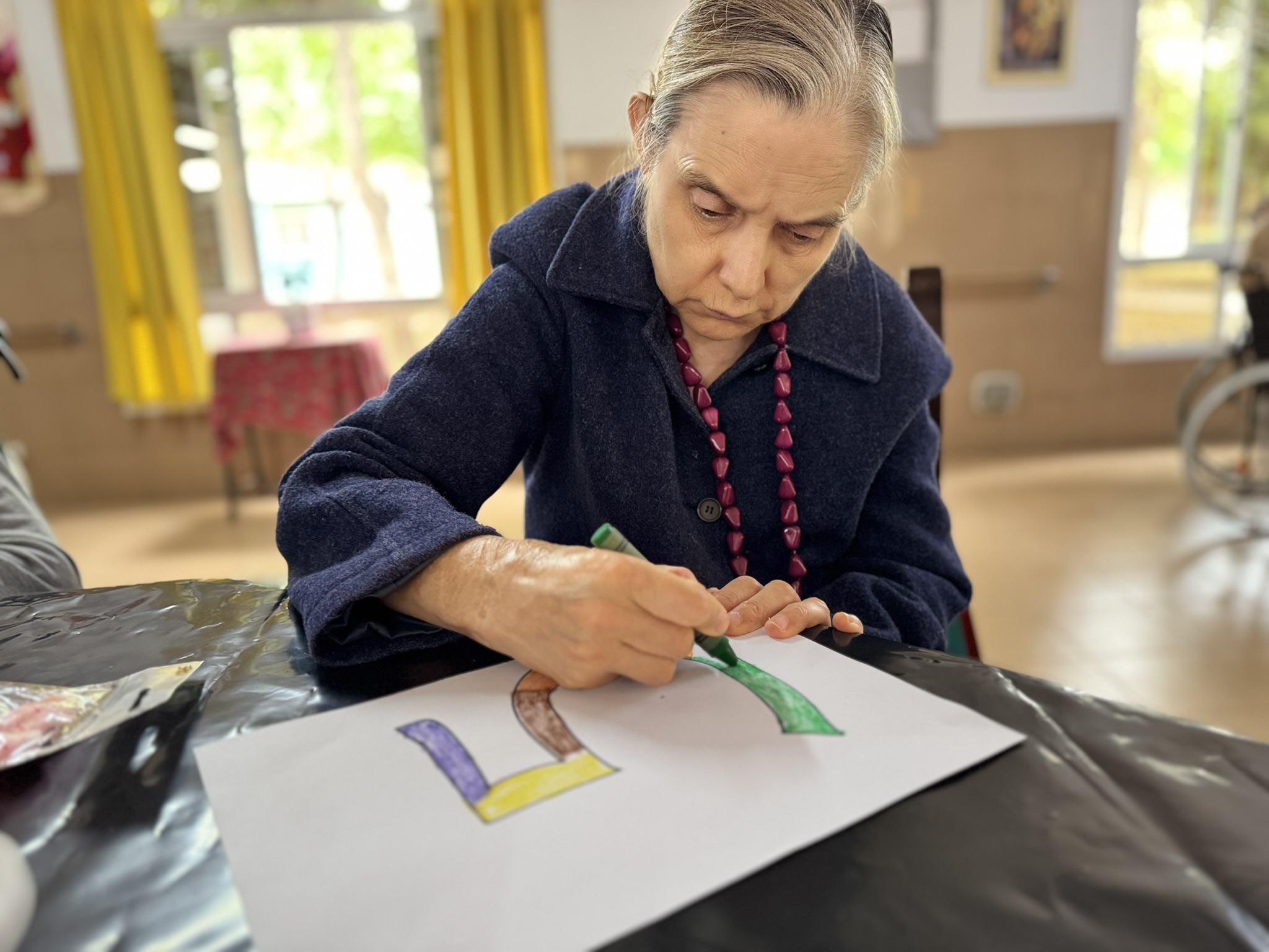 Residente mayor concentrada pintando